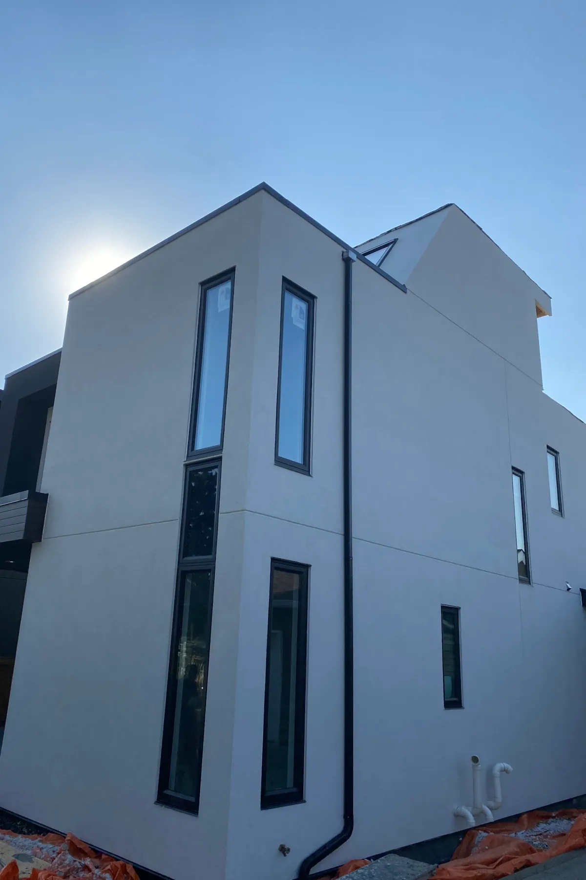 View of a completed beige EIFS wall section with tall, narrow black-framed windows on a modern residential building.