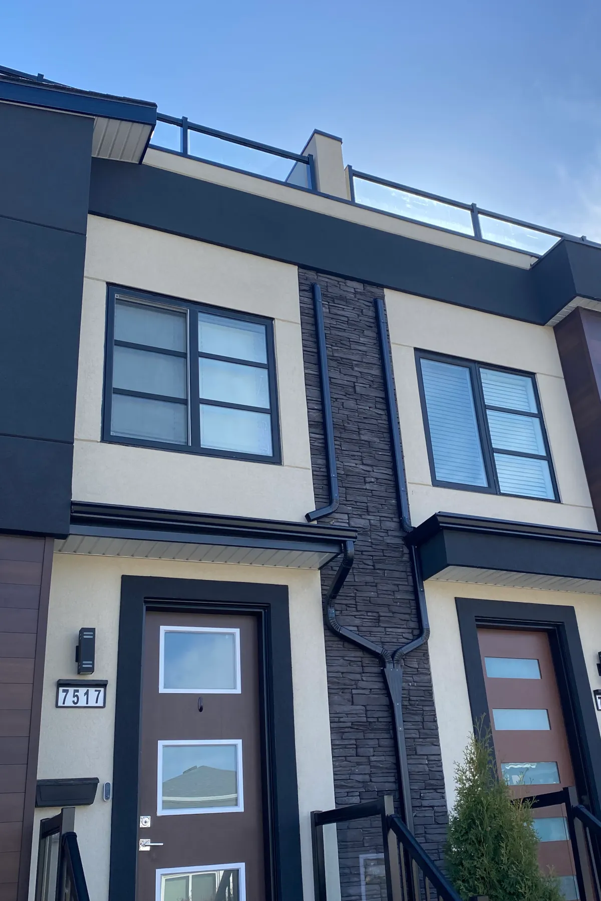 Close-up of charcoal stack stone culture stone used as a vertical accent between two units of a beige stucco triplex.