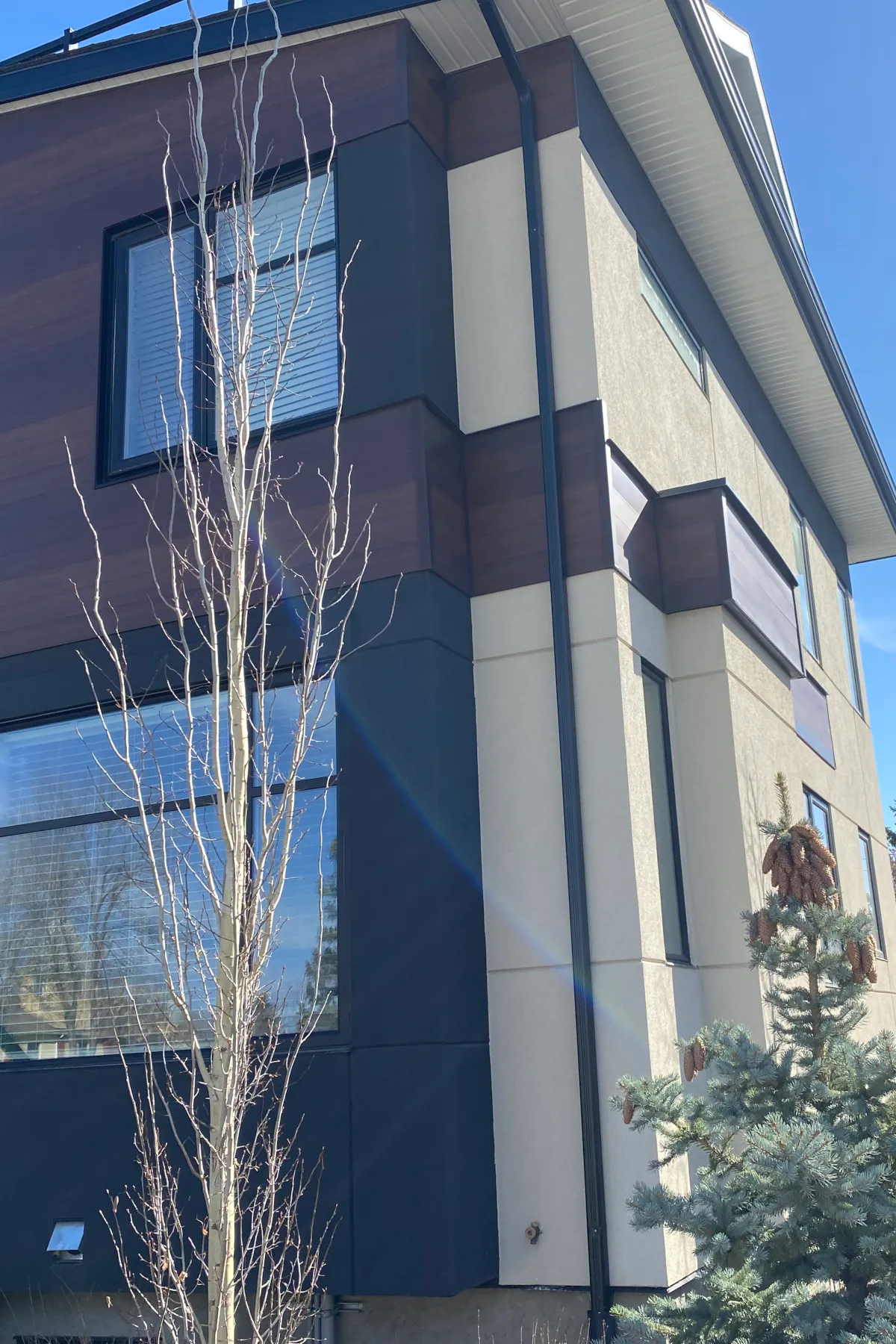 Side view of the triplex showing the application of beige acrylic stucco with consistent horizontal aesthetic grooves.