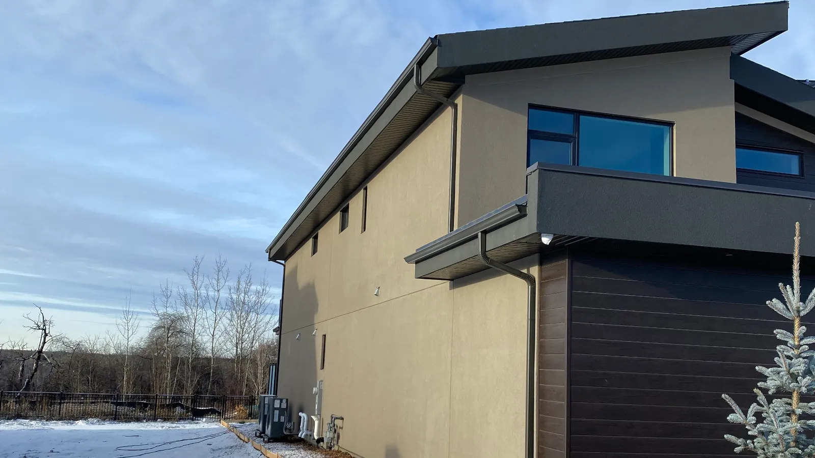 Exterior view of a modern-style house utilizing beige stucco with light golden culture stone accents.