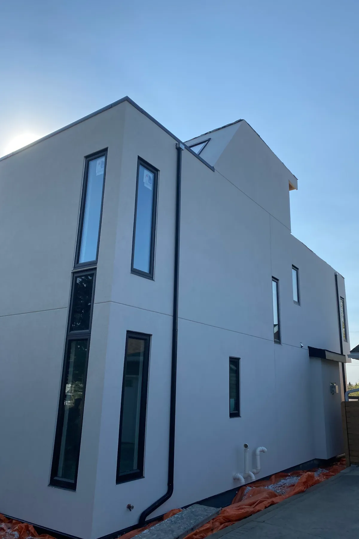 Side profile of a light beige acrylic stucco home showing clean vertical lines and a horizontal aesthetic groove joint.
