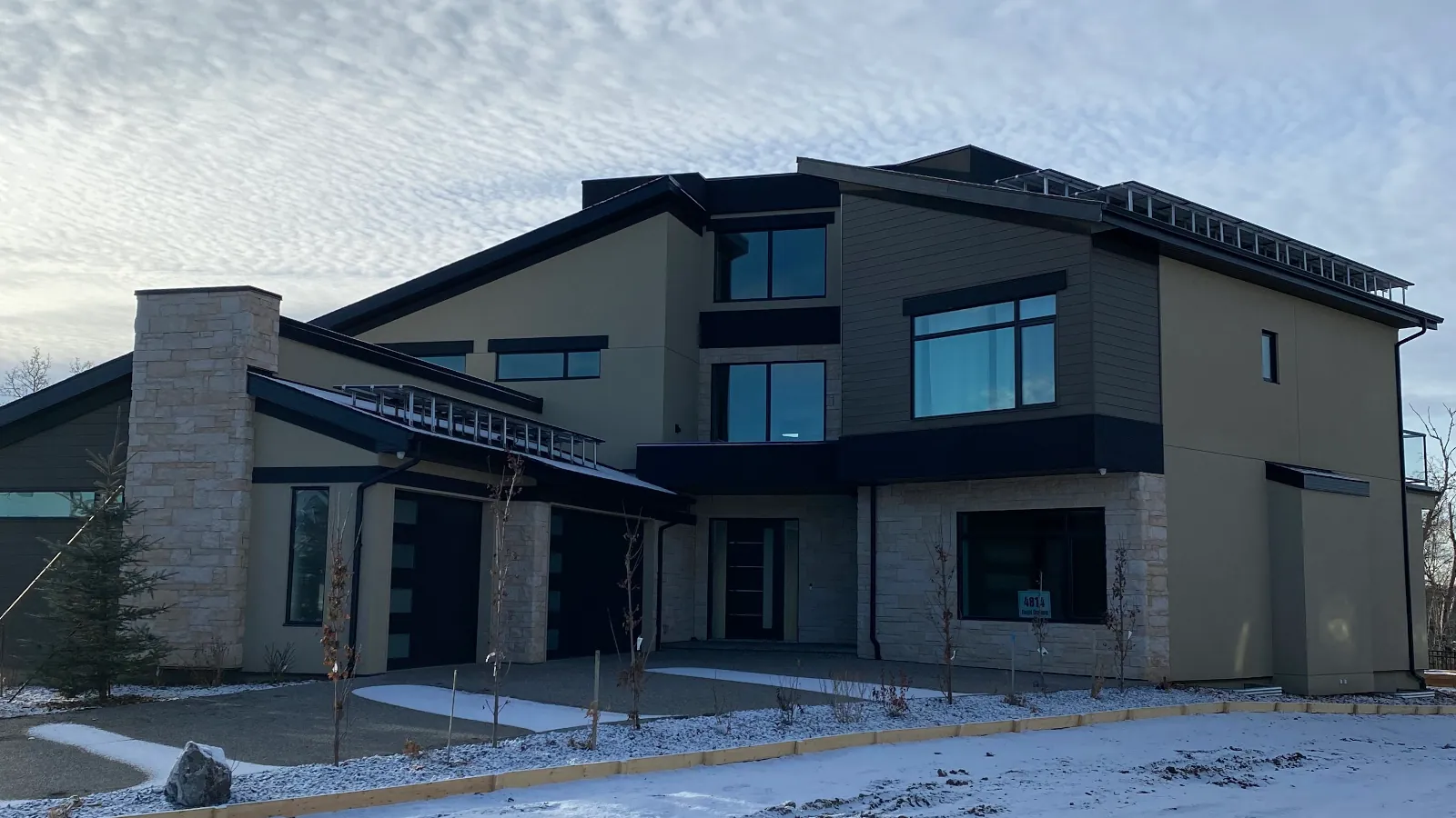 Front elevation showing the combination of acrylic stucco, stacked masonry stone, and wood siding accents.