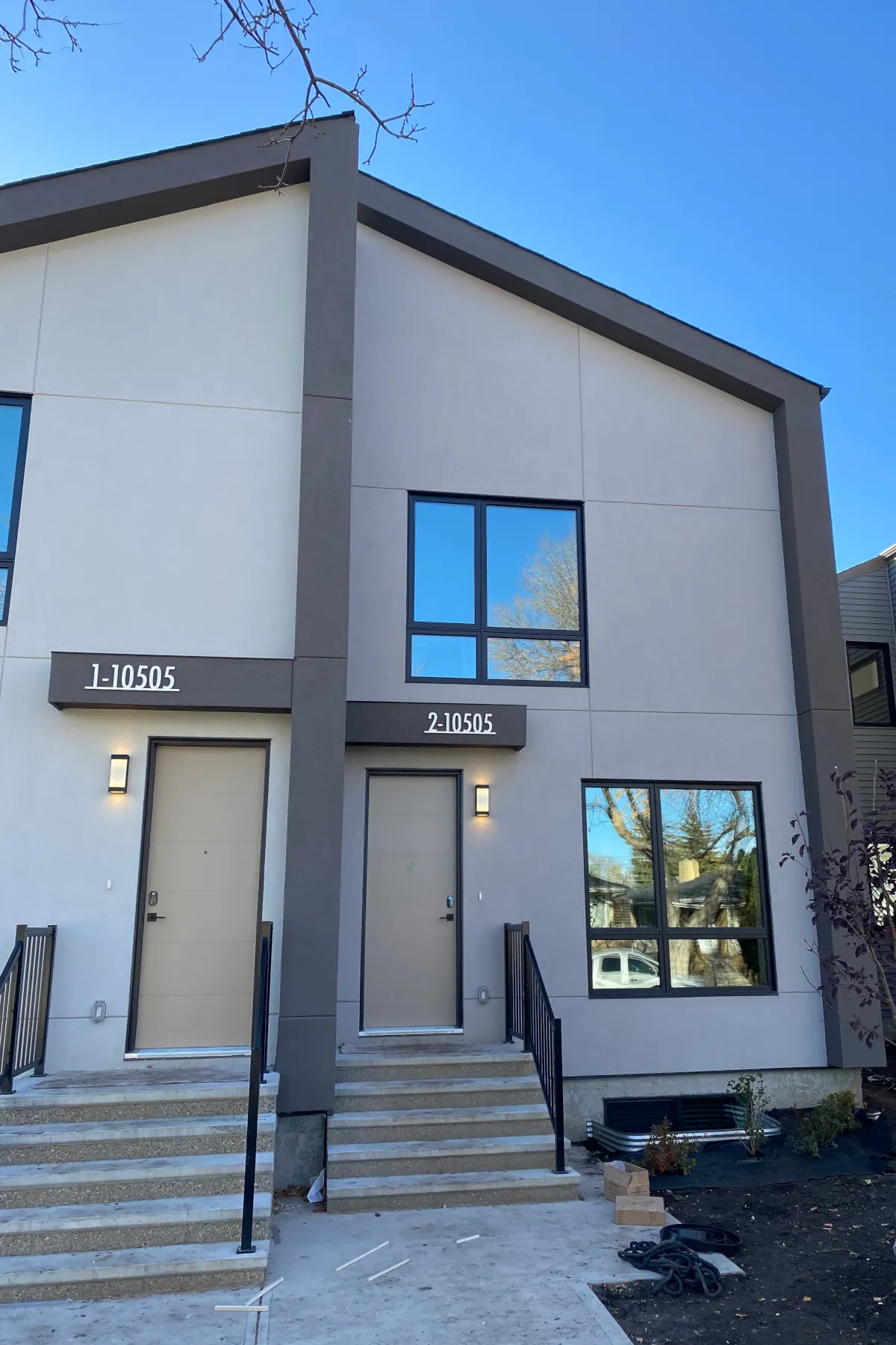 Close-up of the front entrance and windows of a duplex showing the contrast between light and dark grey acrylic stucco finishes.